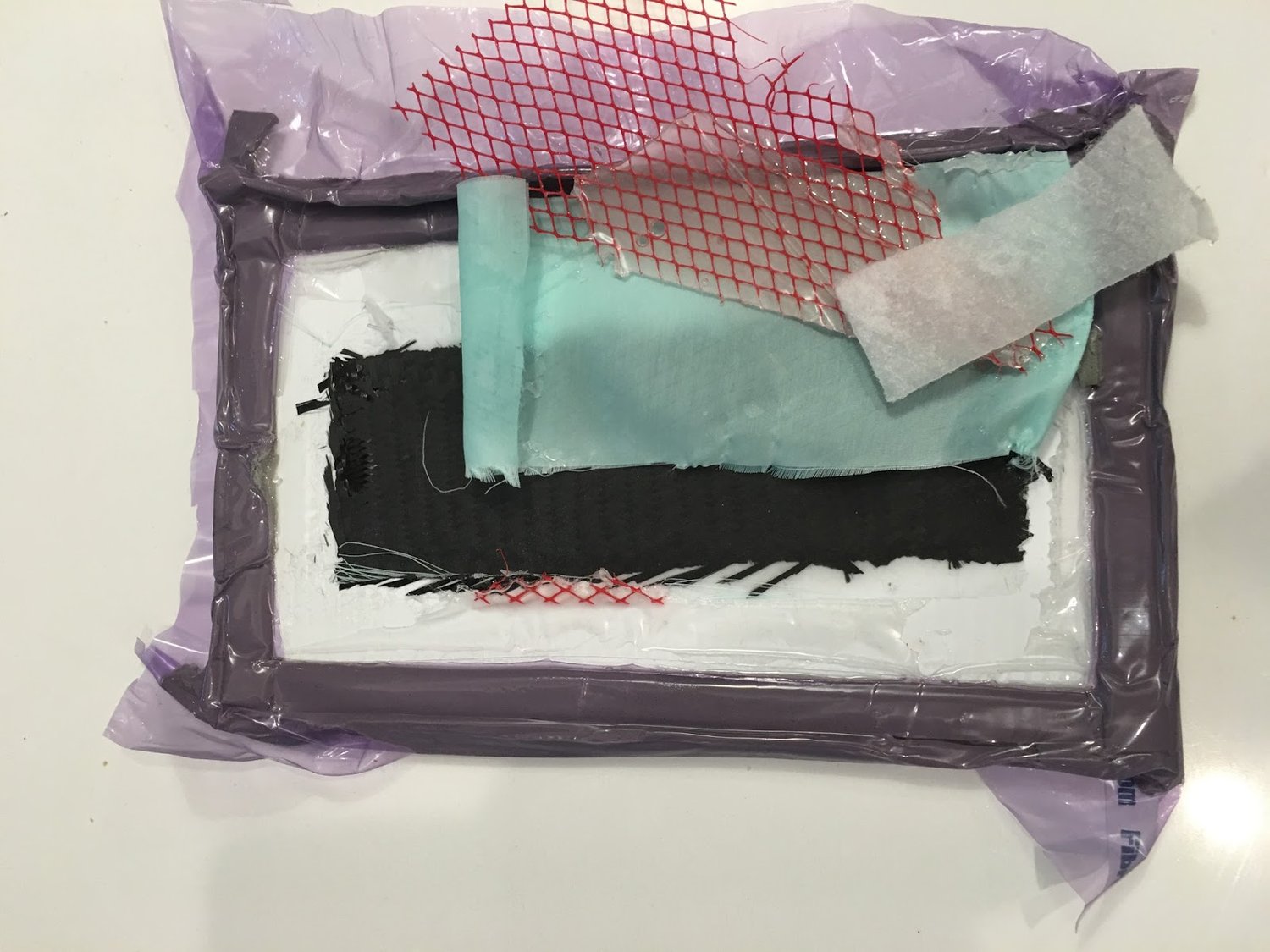 Contents of the vacuum bag: Stiff backing board (white);&nbsp; Carbon fiber (black);&nbsp; Peel ply (green) - removed after infusion;&nbsp; Flow media (red) - removed after;&nbsp; Absorbent batting (white) - removed after;&nbsp; Vacuum bag (purple);…