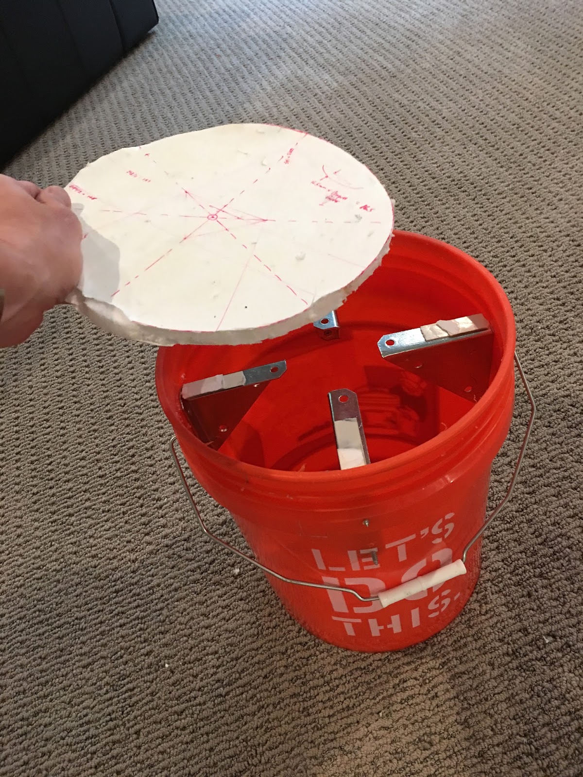 Inserting upper side of mold into bucket. Metal brackets are covered with foam tape. This whole assembly will be turned upside down during molding. Foamcore board is a little chewed up because I took this pic after de-molding 2 pads.